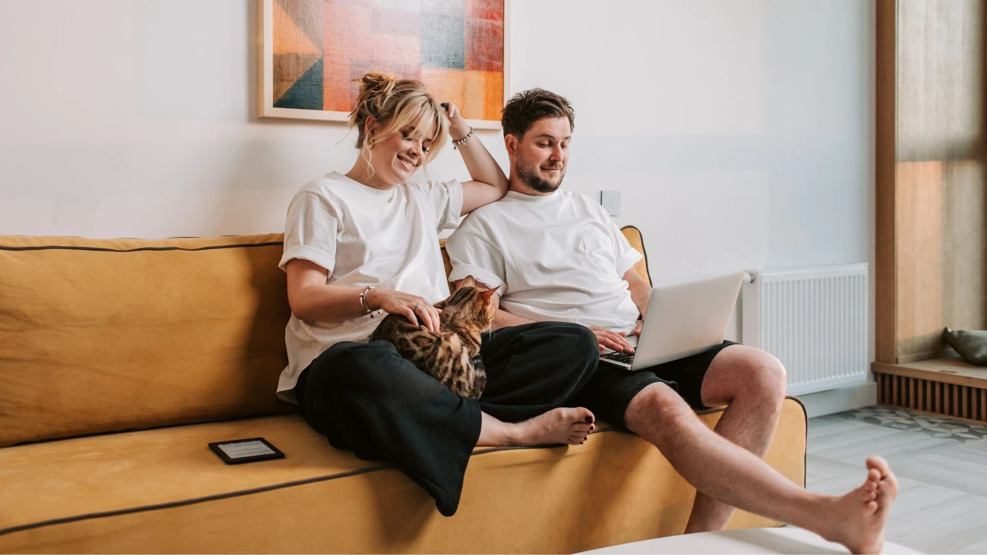 A couple on a sofa at home looking at a laptop together